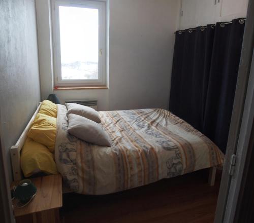una camera da letto con letto, cuscini e finestra di Gite Noisette, Saint André d'Embrun a Embrun