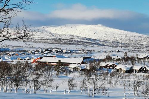 un pueblo cubierto de nieve con una montaña en el fondo en Stor super leilighet - bakkeplan - barnevennlig - 80m2 - selvhushold - vaskefirma en Hovden