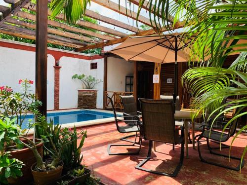 een patio met een tafel en stoelen en een parasol bij Casa de descanso Bacalar in Bacalar