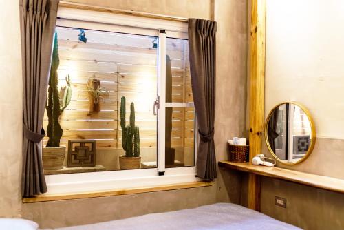 a bedroom with a window with cactuses and a mirror at 唯識禪居-訂房後需聯繫轉帳 in Tainan
