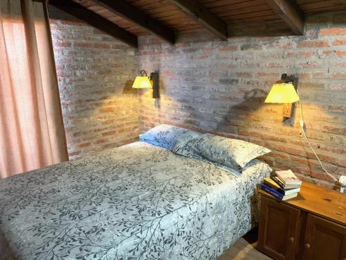 um quarto com uma cama e 2 candeeiros numa parede de tijolos em Complejo Vidas del Mar em Punta Del Diablo