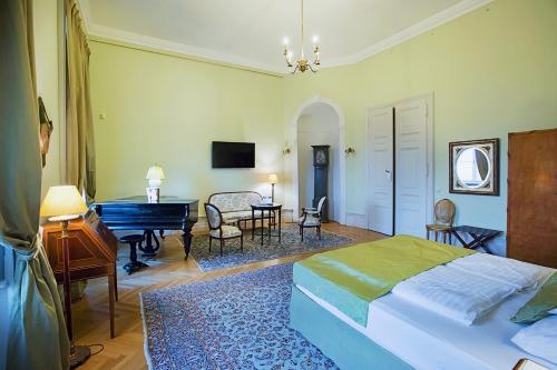 a bedroom with a bed and a desk and a piano at Károlyi Kastély Hotel & Restaurant in Fehérvárcsurgó