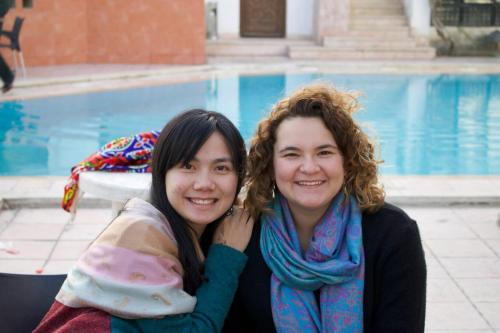 two women are posing for a picture in front of a pool at Six Corners Resort in Abū Sulţān