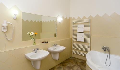 a bathroom with two sinks and a tub and a mirror at Károlyi Kastély Hotel & Restaurant in Fehérvárcsurgó
