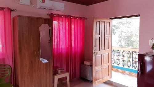 una habitación con cortinas rosas y una puerta en Noel Guest House, en Marmagao