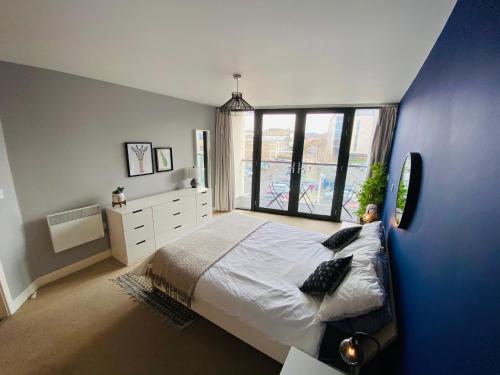 een slaapkamer met een groot bed en een groot raam bij Stewart St James Walk Apartment in Cheltenham