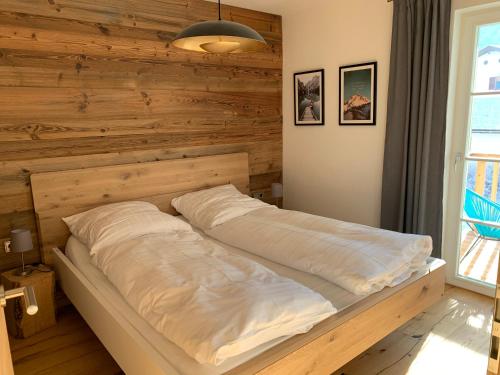 un lit dans une chambre avec un mur en bois dans l'établissement Ferienwohnung Geisberg - Moderne Wohnung mit alpinem Flair in Traumlage, à Schönau am Königssee