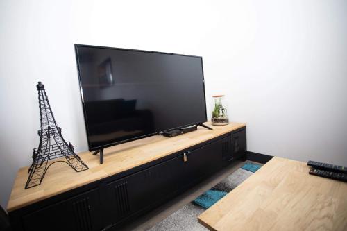 a flat screen tv sitting on top of a wooden entertainment center at Le ptit coin de la Baie in Fort-Mahon-Plage