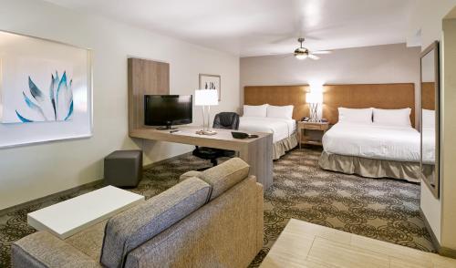 Holiday Inn Hotel & Suites Chihuahua, an IHG Hotel في تشيواوا: غرفة فندقية بسريرين واريكة