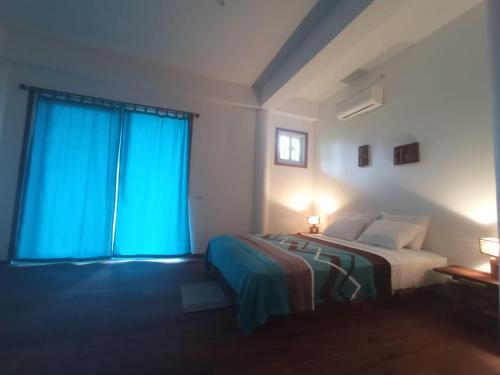 a bedroom with a bed and a window with blue curtains at La Luciernaga Big Creek in Bocas del Toro