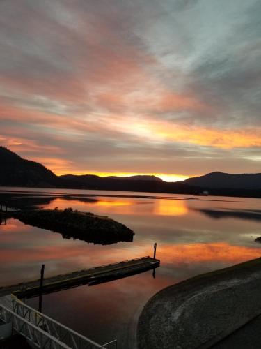 a sunset over a body of water with a dock at Oceanfront Suites at Cowichan Bay in Cowichan Bay