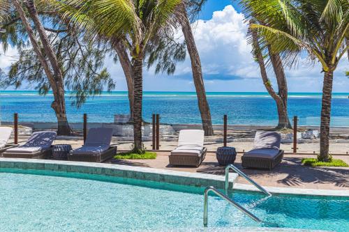 a swimming pool with chaise lounge chairs and the ocean at Oceana Atlântico Hotel & SPA in João Pessoa