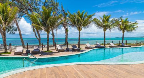 una piscina con palmeras, sillas y el océano en Oceana Atlântico Hotel, en João Pessoa