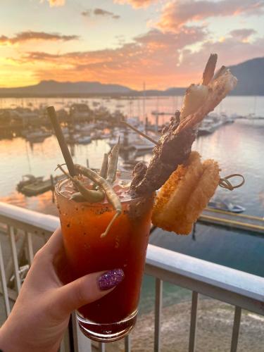 a person holding a drink with a view of the ocean at Oceanfront Suites at Cowichan Bay in Cowichan Bay