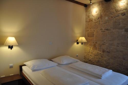 a bedroom with a bed with two pillows and two lights at Hotel Carpymore in Biograd na Moru