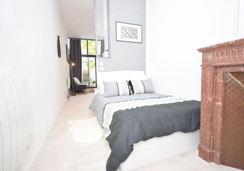 ein weißes Schlafzimmer mit einem Bett und einem Kamin in der Unterkunft HYPER CENTRE VALENCIENNES - WIFI - TERRASSE - TRAMWAY - leRelaisdOdile2 in Valenciennes