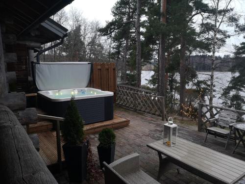 a hot tub on a deck with a table and a bench at Pohjolantuvat in Gerknäs