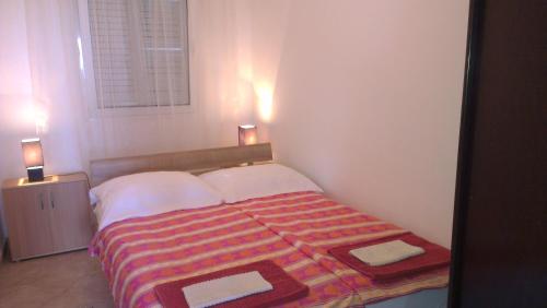 a small bedroom with a bed and two lamps at Apartman Somun in Lopar