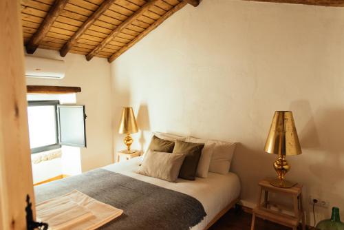 ein Schlafzimmer mit einem Bett mit zwei Lampen und einem Fenster in der Unterkunft Azeite de Marvão, Olivoturismo casa Venda do Lagar in Marvão