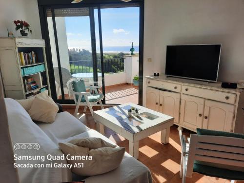 een woonkamer met een bank, een tv en een tafel bij AIRUNNES Atico duplex Zahara primera linea in Zahara de los Atunes