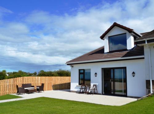 a white house with a patio and a fence at Béal na Banna in Coleraine