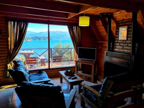 a living room with a large window with a view of the water at Cabañas Aucaman in Villa Pehuenia