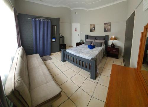 a bedroom with a bed and a couch at Sleepover @194 in Rustenburg