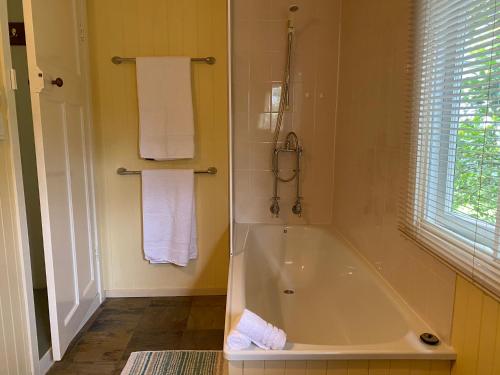 a bathroom with a tub and a shower with towels at Big Fella Wines & Accommodation in Stanthorpe