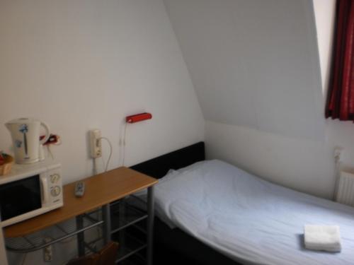 a small room with a bed and a desk at Hostel Pension Tivoli in Groningen