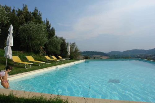 a person standing next to a large swimming pool at Tenuta Il Tresto in Poggibonsi