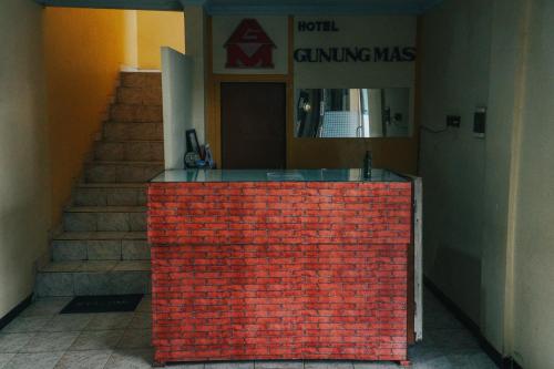 a red brick wall in front of a building with stairs at Hotel Gunung Mas Syariah in Dieng