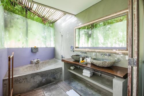 a bathroom with two sinks and a tub and a window at Blue Karma Dijiwa Seminyak in Seminyak