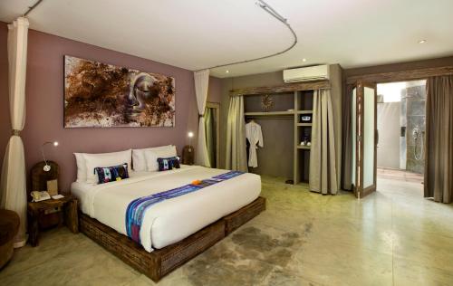 a bedroom with a large bed with a painting on the wall at Blue Karma Dijiwa Seminyak in Seminyak