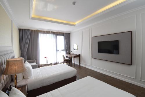 a hotel room with two beds and a flat screen tv at Phu Cuong Hotel Ca Mau in Cà Mau