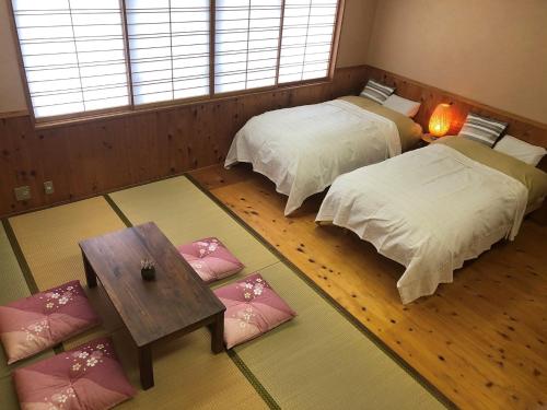 Zimmer mit 2 Betten und einem Tisch in der Unterkunft のと海 in Nanao