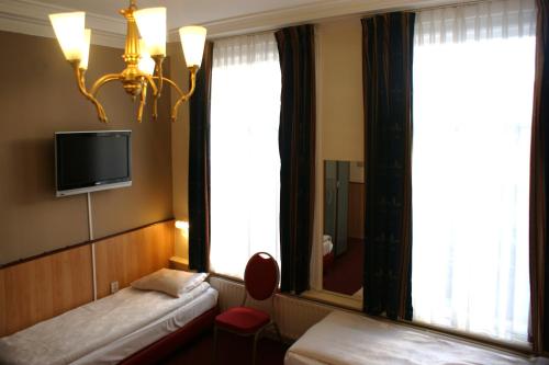 a hotel room with two beds and a tv on the wall at Hotel de Westertoren in Amsterdam