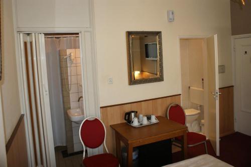 La salle de bains est pourvue d'une table, de chaises et d'un miroir. dans l'établissement Hotel de Westertoren, à Amsterdam