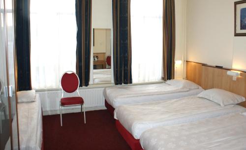 a hotel room with two beds and a red chair at Hotel de Westertoren in Amsterdam