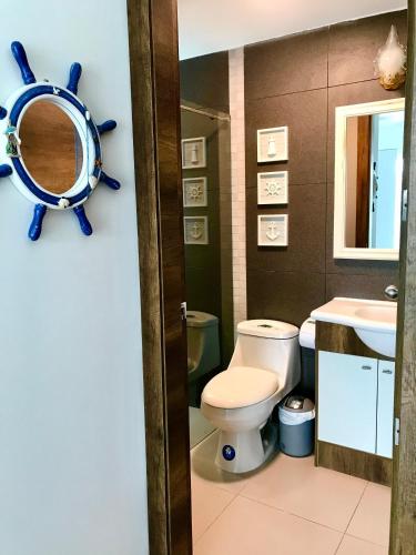 a bathroom with a toilet and a sink and a mirror at RESORT PLAYA AZUL 2 dormitorios in Tonsupa