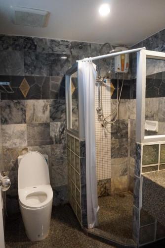 a bathroom with a toilet and a shower stall at Rockgarden Beach Resort in Mae Pim
