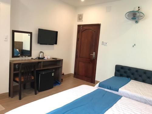 a bedroom with two beds and a desk and a mirror at Hotel Hoàng Hưng Quy Nhơn in Quy Nhon