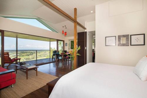 a bedroom with a bed and a living room with a view at Byron's Secret in Coorabell Creek