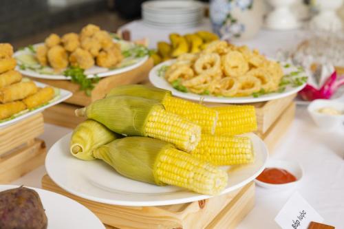 a table topped with plates of corn on the cob at Casa Maya Resort in ThÃ´n Báº£o An