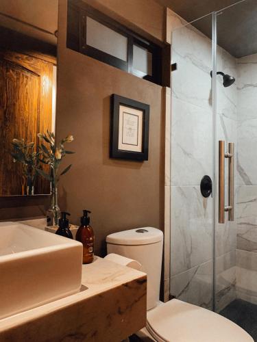 a bathroom with a toilet and a glass shower at CASA EMILIA B&B Boutique in Mexico City