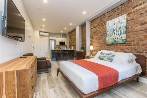a bedroom with a large bed and a brick wall at Lofts du Parc LaHaie in Montréal