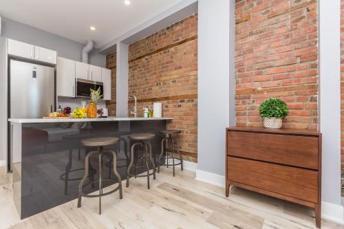 a kitchen with a brick wall and a bar with stools at Lofts du Parc LaHaie in Montréal