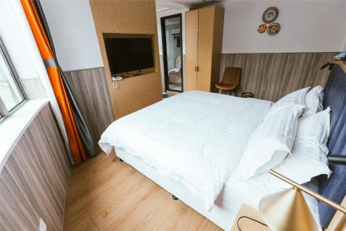 a bedroom with a white bed and a television at Shanghai Fish Inn People Square in Shanghai