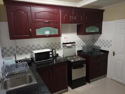 cocina con armarios rojos, fregadero y microondas en Semuya Apartments, en Ndola