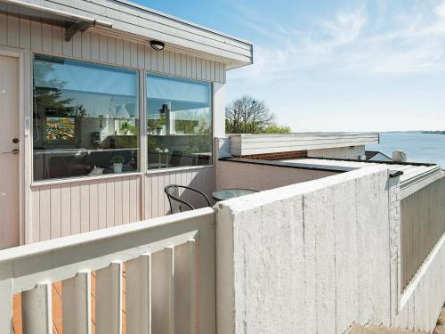 a house with a fence and a balcony with a view of the ocean at 4 person holiday home in Gr sten in Gråsten