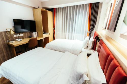 a hotel room with two beds and a desk at Shanghai Fish Inn People Square in Shanghai